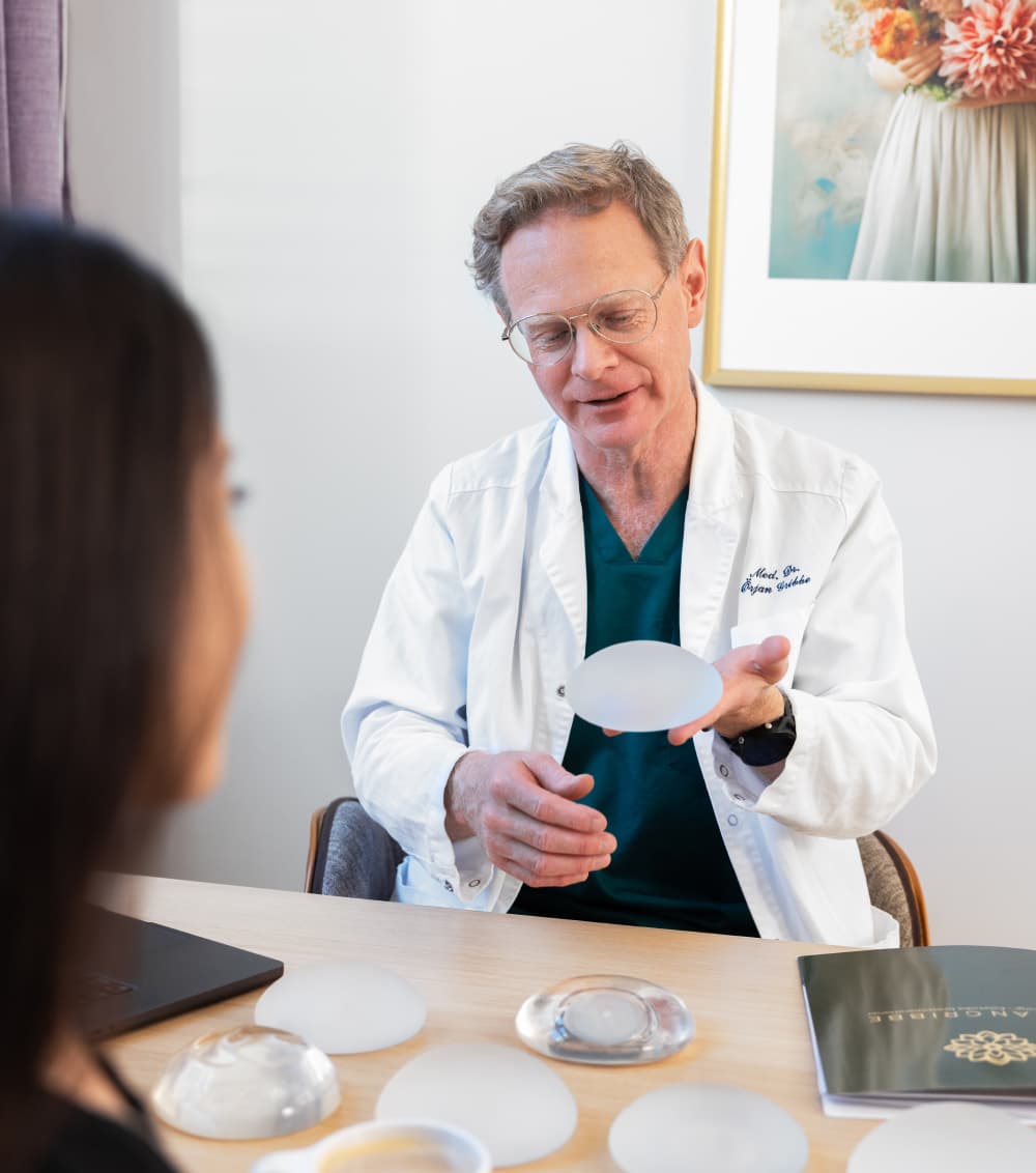 Bild på dr Örjan Gribbe som visar olika bröstimplantat för en patient.