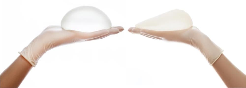 En kirurg i gröna operationskläder visar vägen för en patient klädd i vit morgonrock och grön operationsmössa i en sjukhuskorridor med ljus belysning.